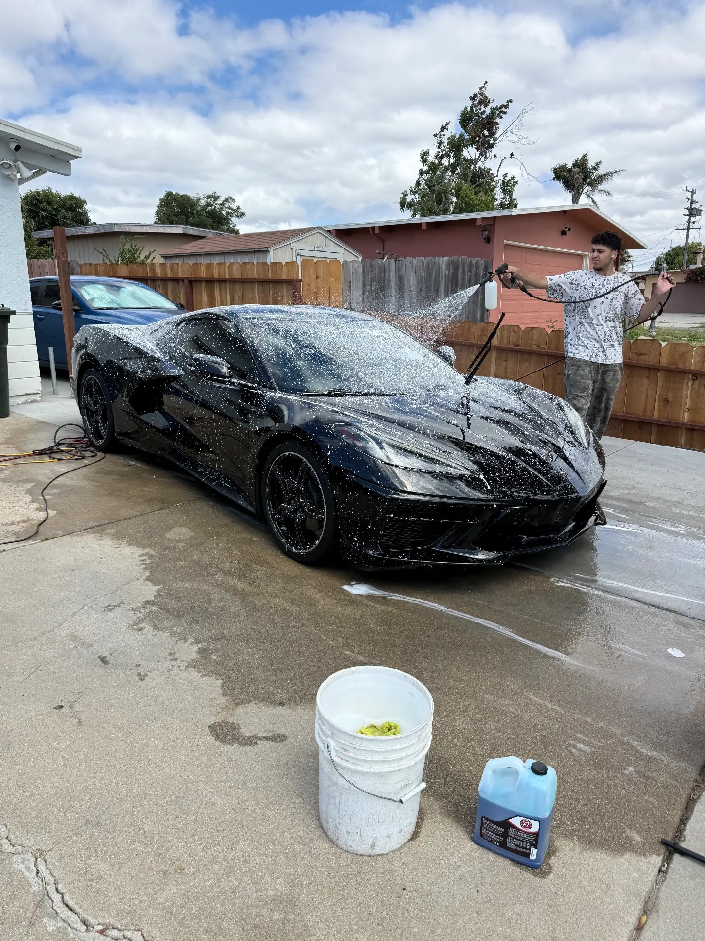 Mobile detailer washing a black Ferrari in a Monterey driveway