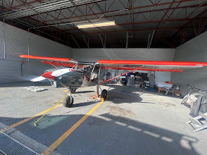 Red and white aircraft being detailed inside a hangar near Monterey