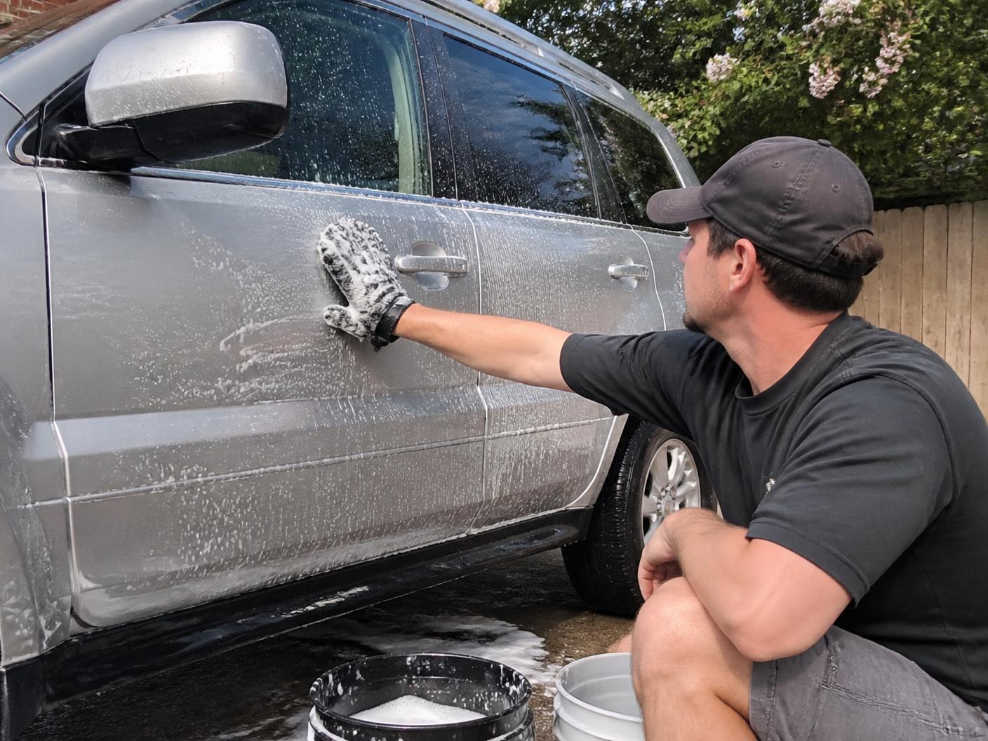 Detailer hand washing a silver BMW SUV during a mobile wash and wax service in Monterey, CA