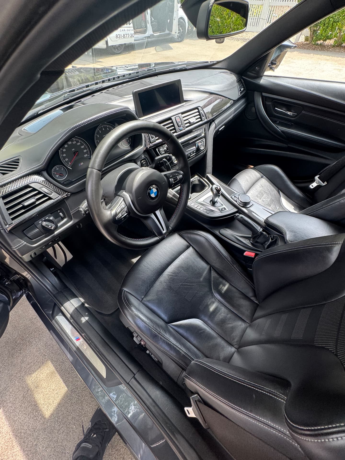 Detailed BMW driver area with conditioned black leather and spotless controls